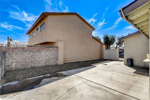 view of property exterior featuring a patio, fence, and stucco siding