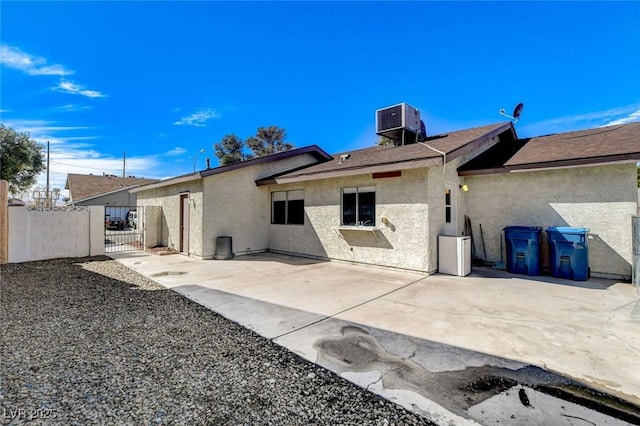 rear view of house with a gate, stucco siding, fence, and a patio area