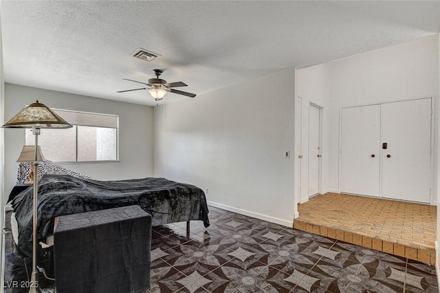 bedroom with visible vents, baseboards, a textured ceiling, and a ceiling fan