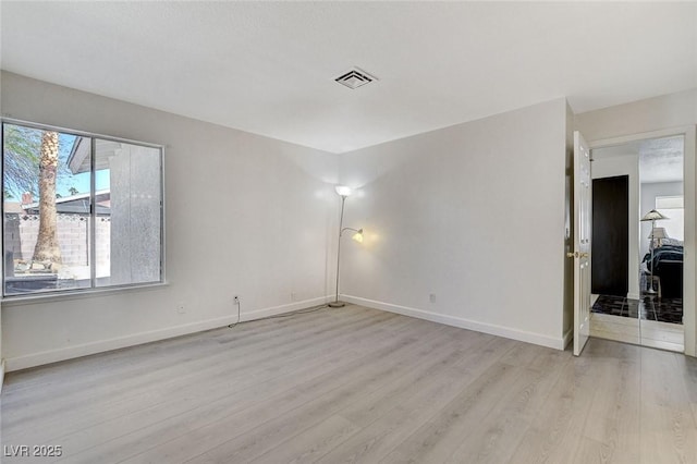 unfurnished room with a wealth of natural light, visible vents, and wood finished floors