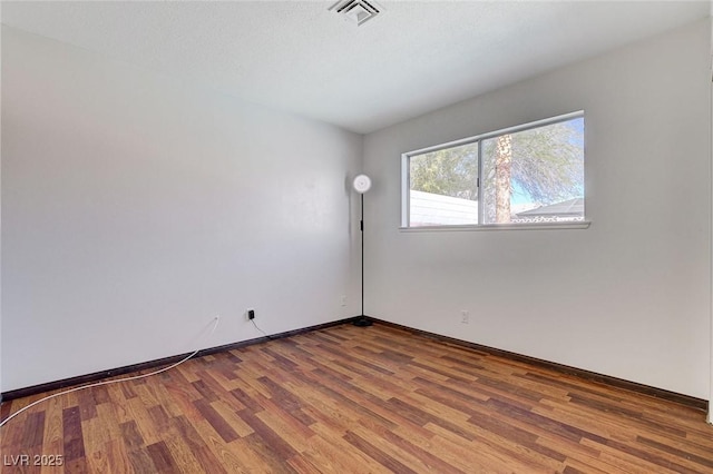 unfurnished room featuring visible vents, baseboards, and wood finished floors