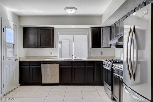 kitchen featuring light tile patterned flooring, a sink, light countertops, under cabinet range hood, and appliances with stainless steel finishes