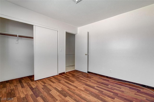 unfurnished bedroom featuring wood finished floors, a closet, and a textured ceiling