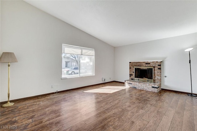 unfurnished living room with a fireplace, vaulted ceiling, wood finished floors, and baseboards