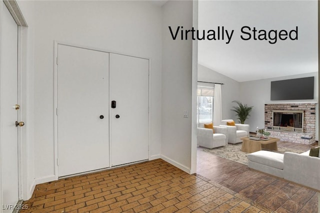 entrance foyer with wood finished floors, a fireplace, baseboards, and high vaulted ceiling