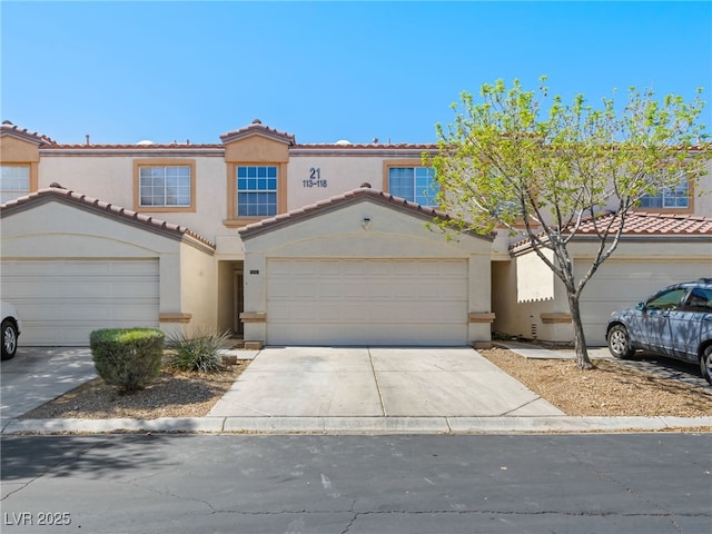 view of front facade with a tiled roof, concrete driveway, stucco siding, and a garage