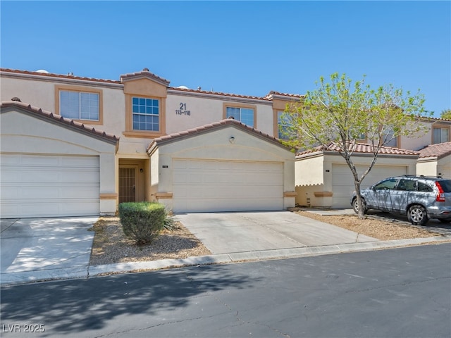 mediterranean / spanish-style house featuring a tiled roof, an attached garage, driveway, and stucco siding