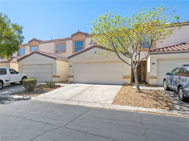 view of front of home featuring stucco siding, a tiled roof, concrete driveway, and a garage