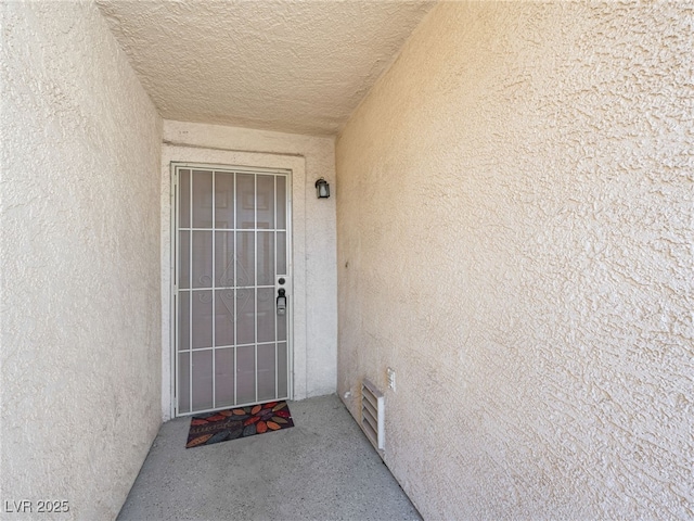 view of exterior entry with visible vents and stucco siding