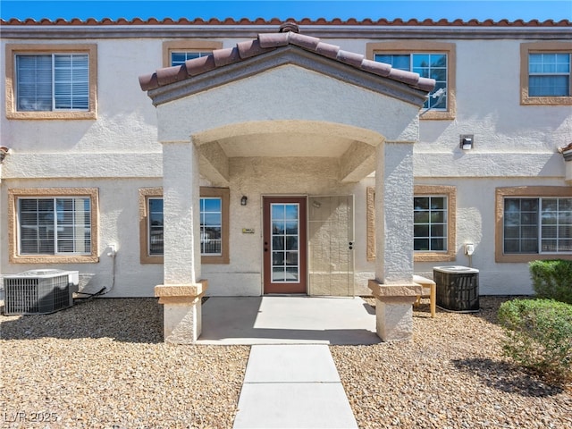 property entrance with central AC and stucco siding