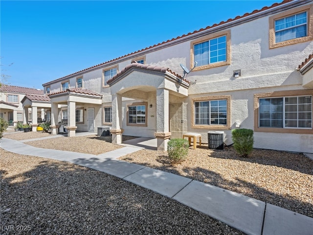 rear view of property with a tiled roof, stucco siding, and cooling unit