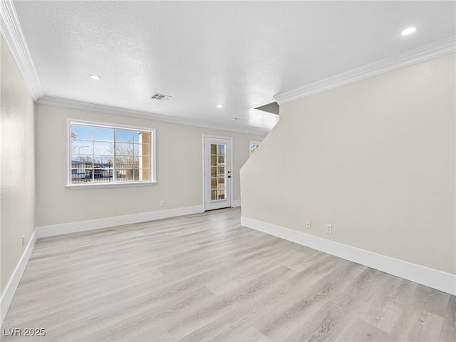 unfurnished room featuring a textured ceiling, visible vents, light wood finished floors, and ornamental molding