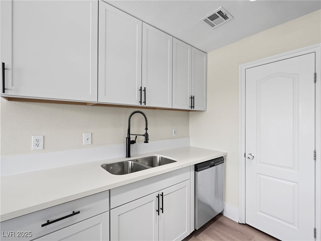 kitchen featuring visible vents, dishwasher, light countertops, white cabinetry, and a sink