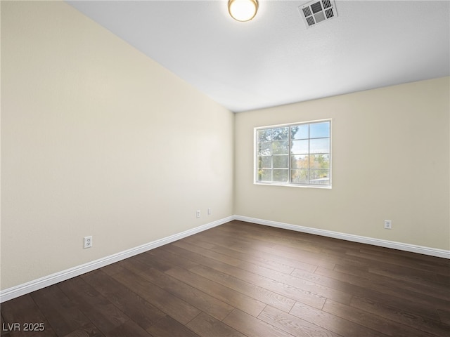 empty room featuring visible vents, baseboards, and dark wood finished floors