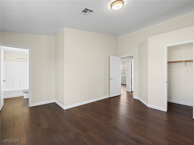 unfurnished bedroom with dark wood-type flooring, visible vents, baseboards, and a closet