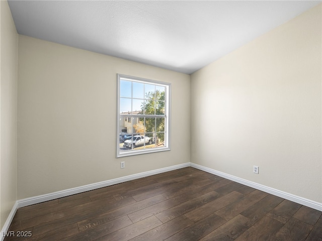 spare room featuring baseboards and dark wood finished floors