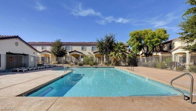 community pool featuring a patio area, fence, and a residential view