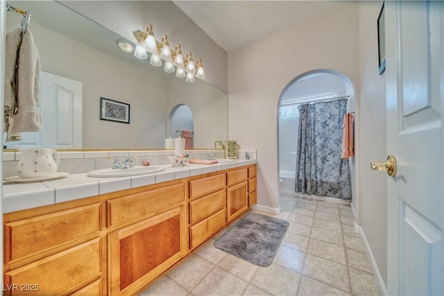 bathroom featuring double vanity, baseboards, and a sink