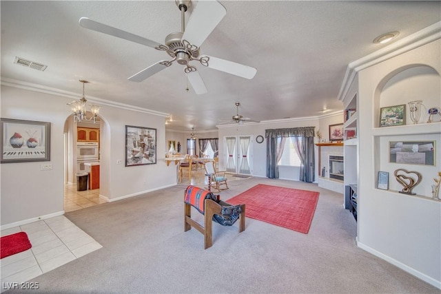 tiled living room featuring visible vents, crown molding, ceiling fan, carpet floors, and arched walkways