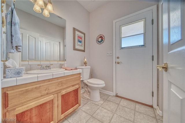 bathroom with tile patterned floors, toilet, tasteful backsplash, baseboards, and vanity