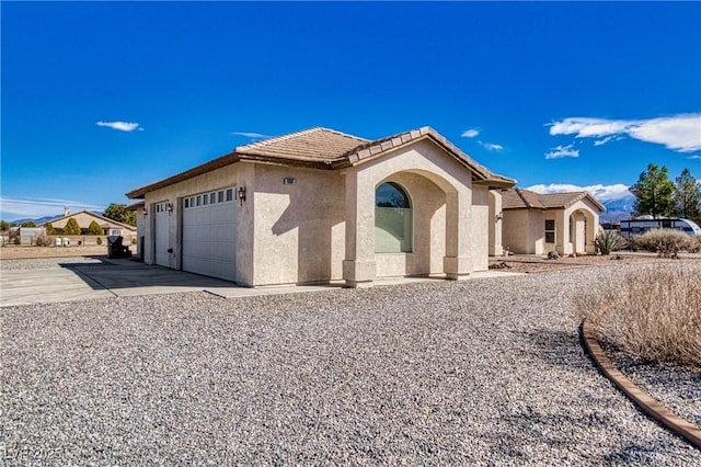 view of front facade featuring stucco siding, concrete driveway, a tile roof, and a garage