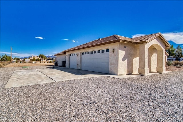 view of home's exterior featuring stucco siding, an attached garage, driveway, and a tiled roof