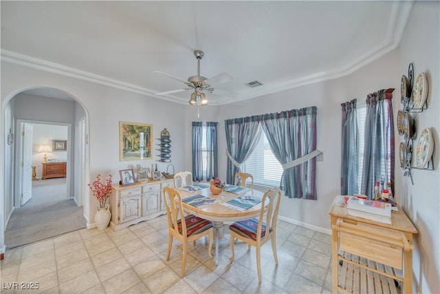 dining room with arched walkways, visible vents, baseboards, and ceiling fan