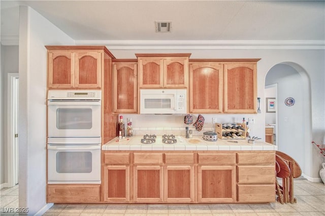 kitchen with visible vents, white appliances, arched walkways, and baseboards