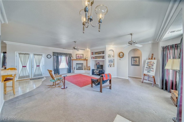 living area featuring carpet floors, ornamental molding, and ceiling fan with notable chandelier