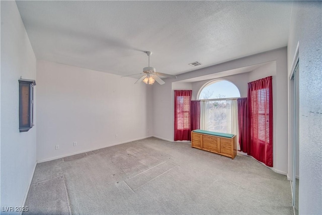 spare room featuring a ceiling fan, baseboards, visible vents, a textured ceiling, and carpet flooring