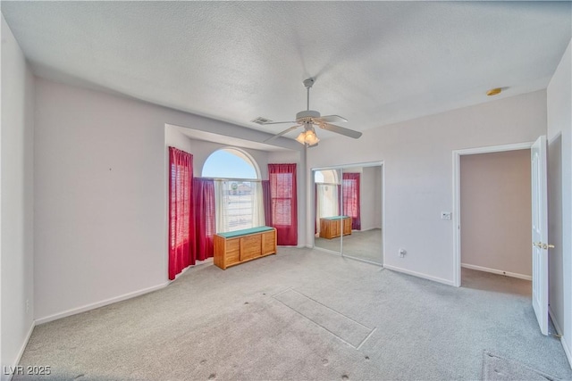 unfurnished bedroom with ceiling fan, a textured ceiling, baseboards, and carpet floors