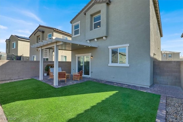 rear view of property with stucco siding, a lawn, a fenced backyard, and a patio area