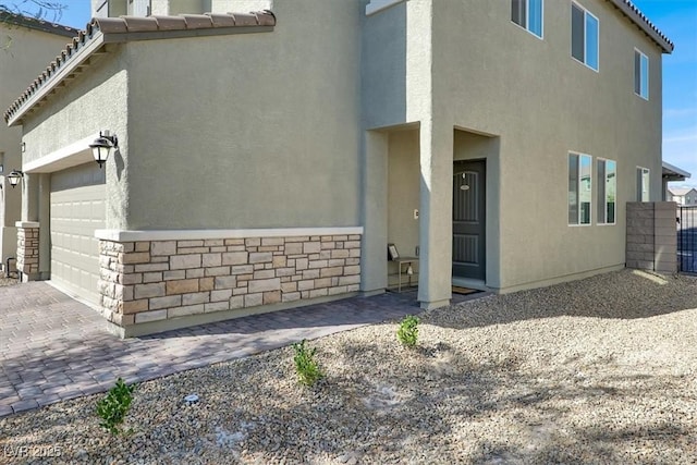 exterior space featuring stucco siding, decorative driveway, a garage, and a tiled roof