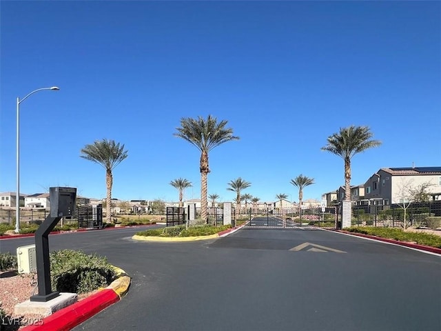 view of road featuring street lighting, a gated entry, a residential view, curbs, and a gate