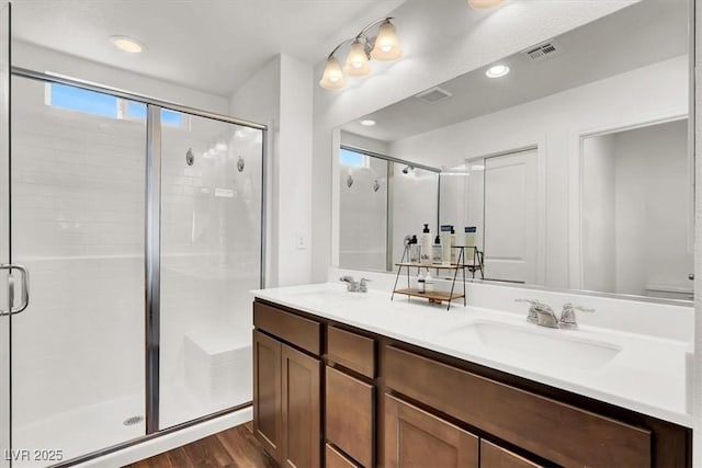 full bath with visible vents, a stall shower, and a sink