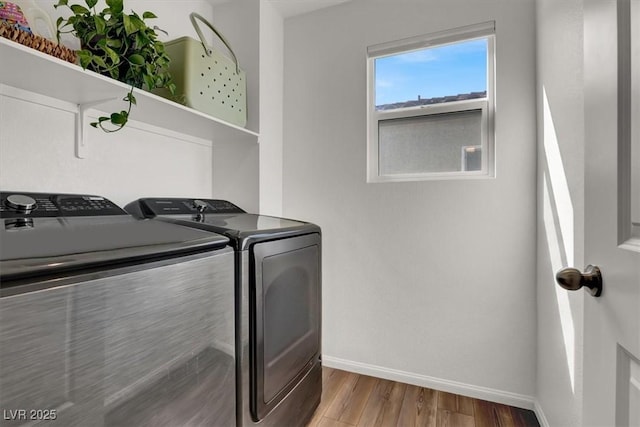 clothes washing area featuring washer and dryer, laundry area, wood finished floors, and baseboards