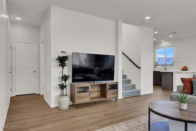 living area with stairs, recessed lighting, baseboards, and light wood finished floors