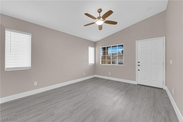 unfurnished room featuring baseboards, lofted ceiling, ceiling fan, and wood finished floors