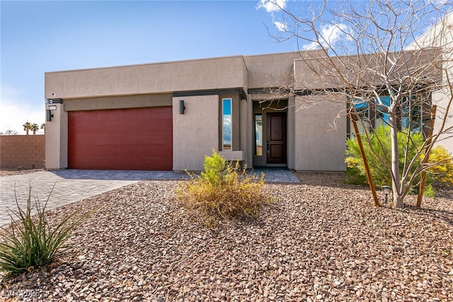 pueblo revival-style home with stucco siding, a garage, and driveway