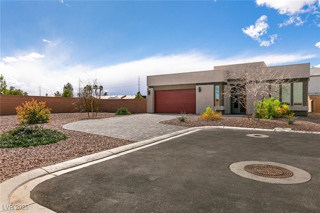 southwest-style home with stucco siding, an attached garage, driveway, and fence