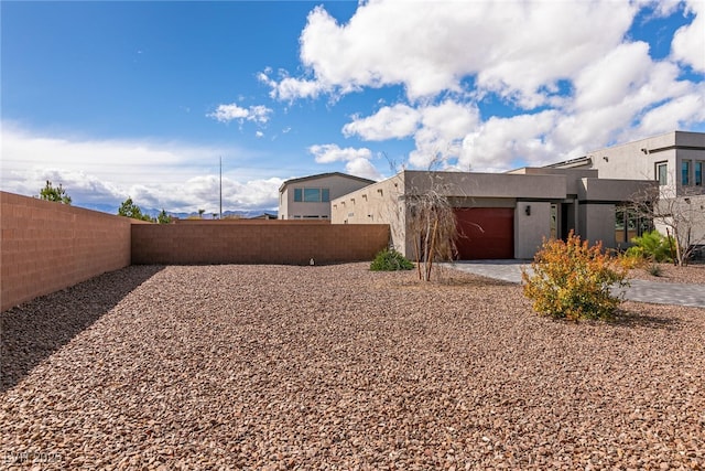 view of yard featuring an attached garage, fence private yard, and driveway