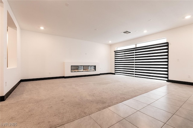 carpeted empty room with a glass covered fireplace, recessed lighting, visible vents, and baseboards