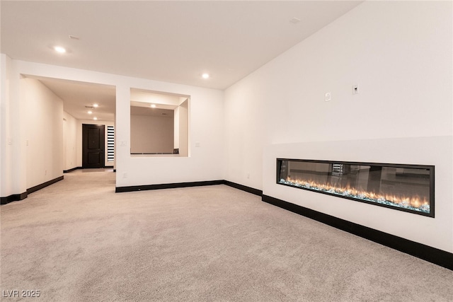 unfurnished living room featuring recessed lighting, baseboards, light carpet, and a glass covered fireplace