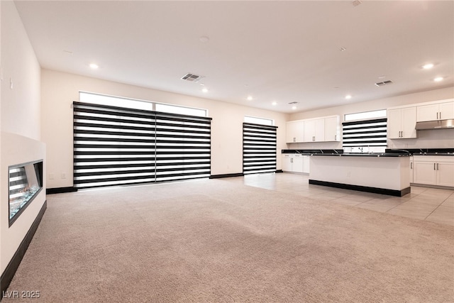 unfurnished living room with recessed lighting, visible vents, and light carpet