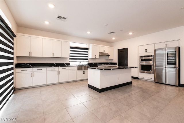 kitchen featuring dark countertops, visible vents, under cabinet range hood, recessed lighting, and appliances with stainless steel finishes