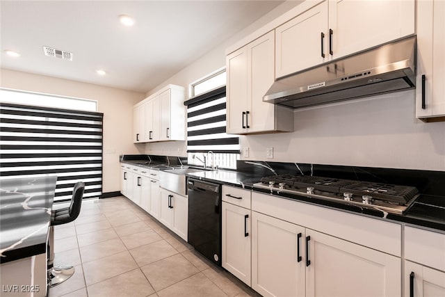 kitchen with dark countertops, black dishwasher, under cabinet range hood, and stainless steel gas cooktop