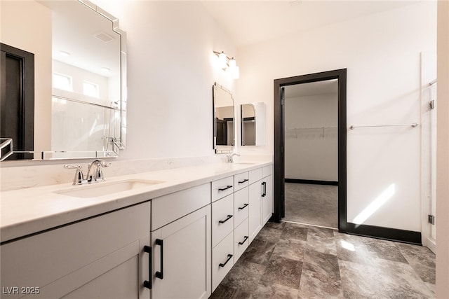 bathroom with double vanity, visible vents, a walk in closet, and a sink