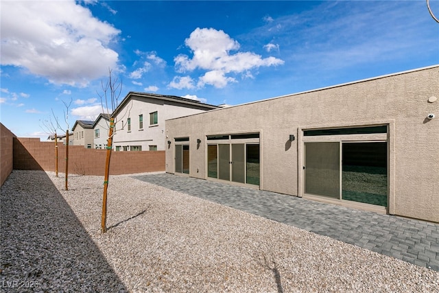 back of house with stucco siding, a fenced backyard, and a patio area