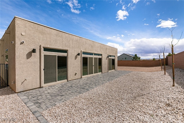 rear view of property featuring stucco siding, a fenced backyard, and a patio area