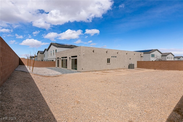 rear view of property with central air condition unit, stucco siding, and a fenced backyard